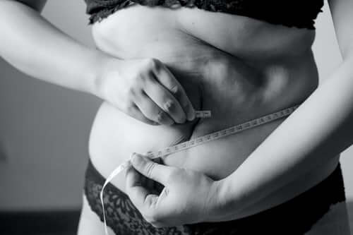 Black and white photo of woman with tape measure around belly
