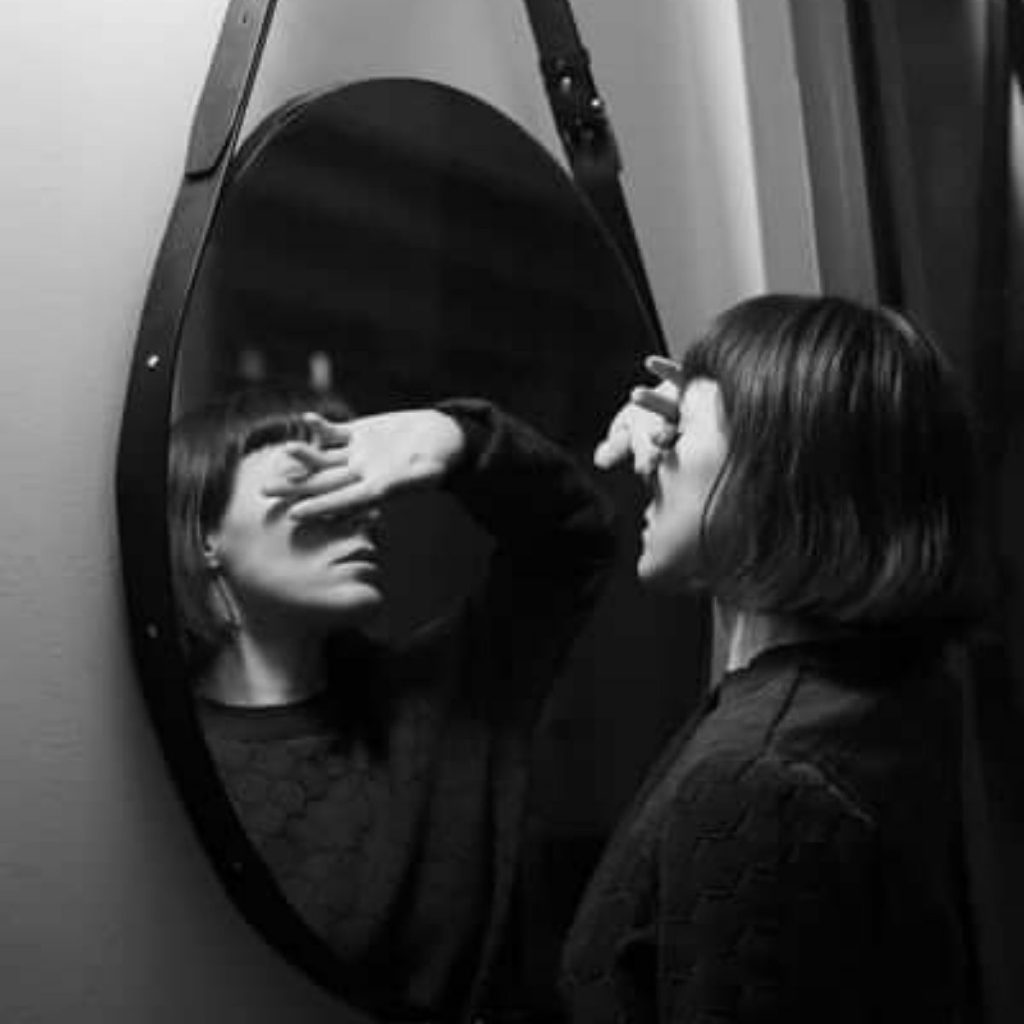 woman in mirror covering eyes