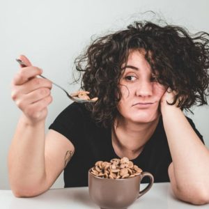 woman disappointed eating cereal