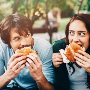 man and woman eating burgers