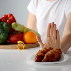 person pushing away breads with a plate of fruit in front of them