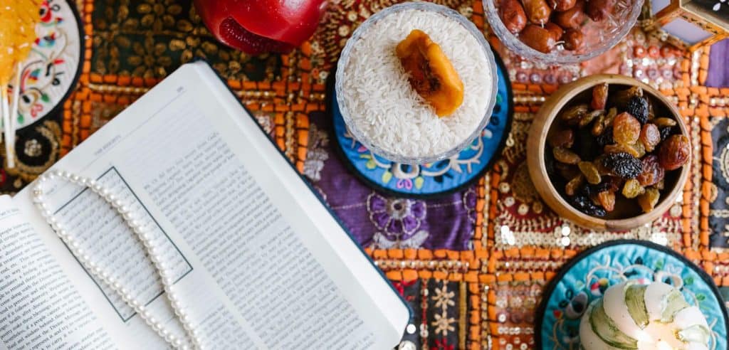 book with pearls surrounded by food on colorful tablecloth