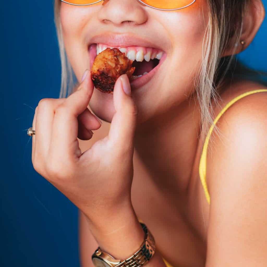 woman smiling and eating fried potato