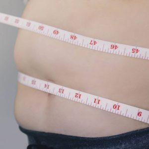 person with measuring tape around waist