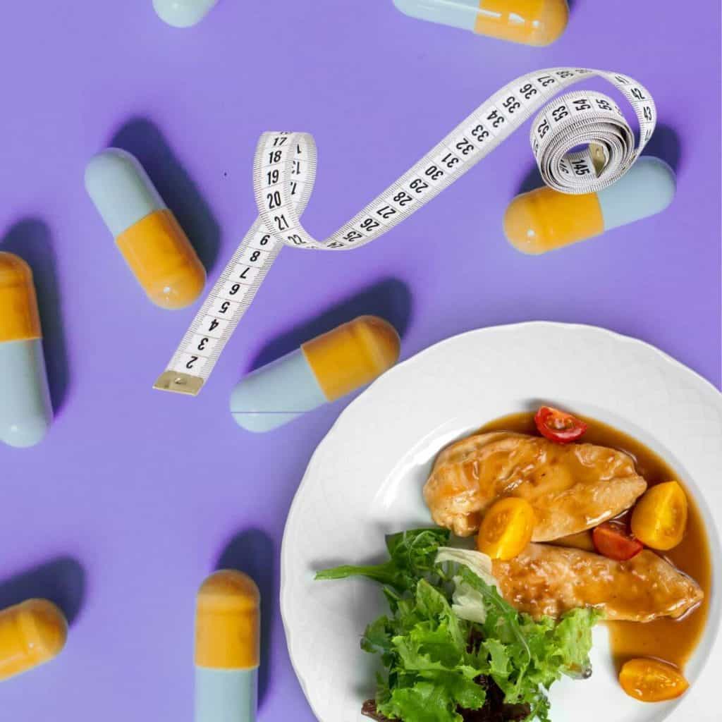 yellow and blue pills on purple background with plate of food and tape measure