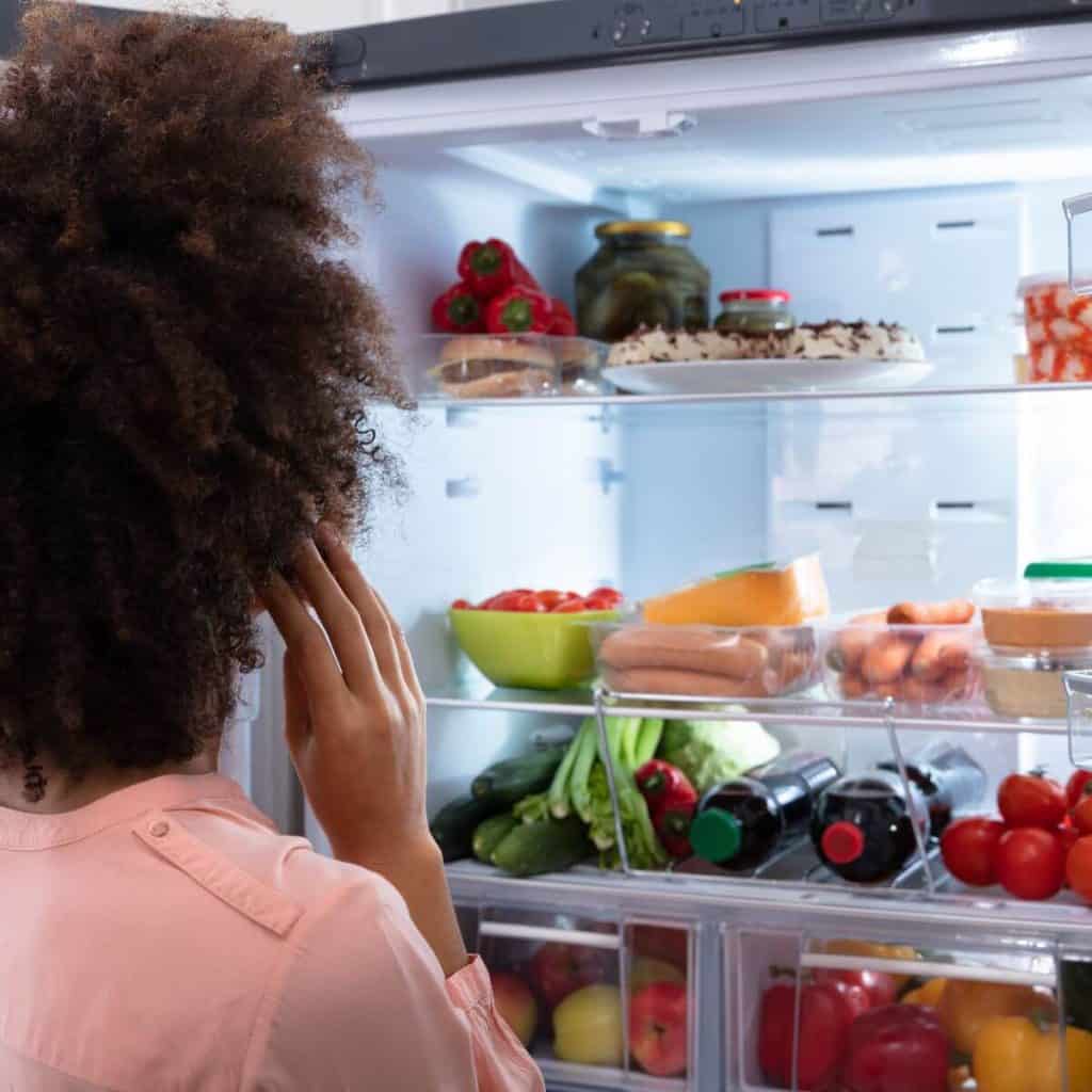 woman with curly brown hair looking in fridge