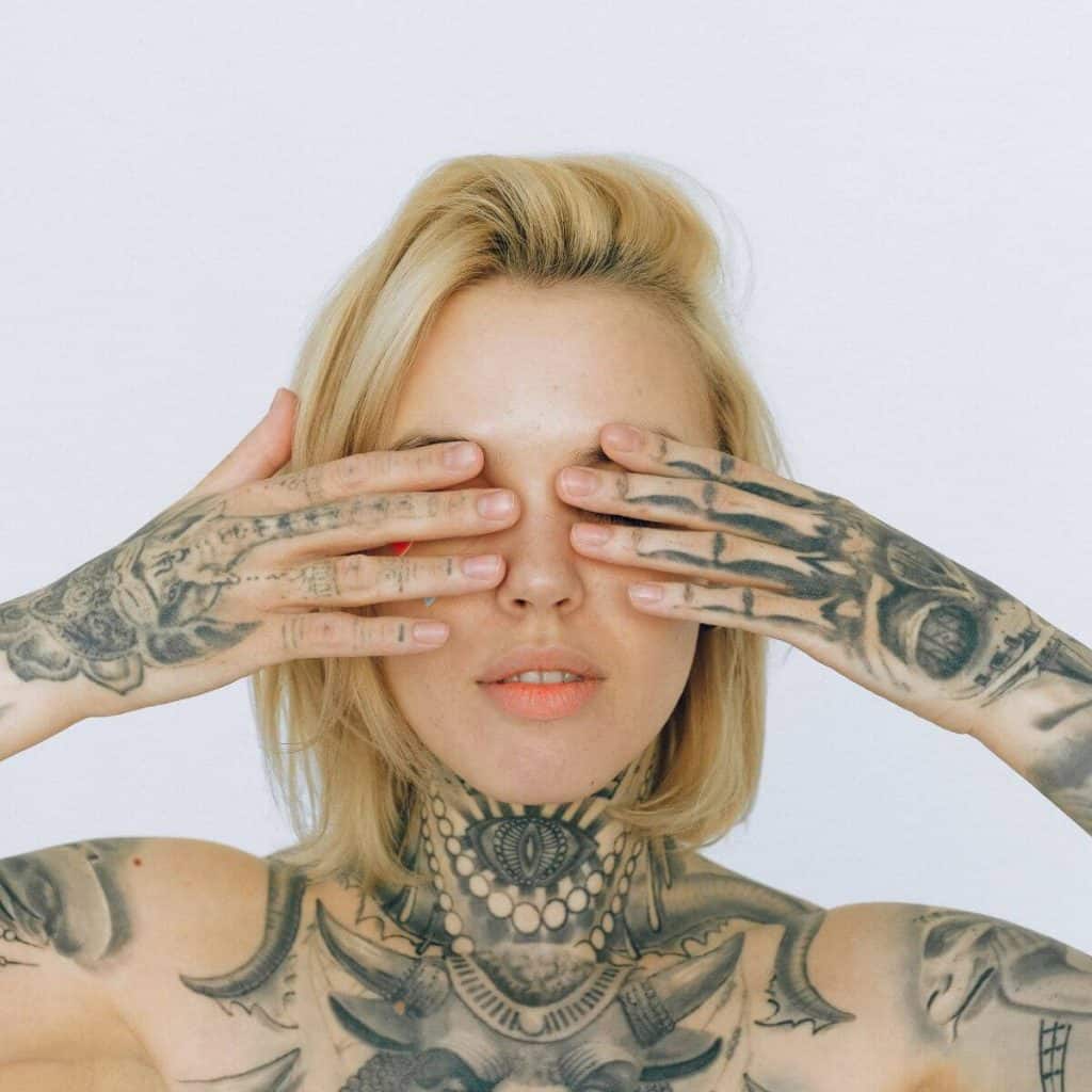 woman with tattoos and blonde hair covering eyes